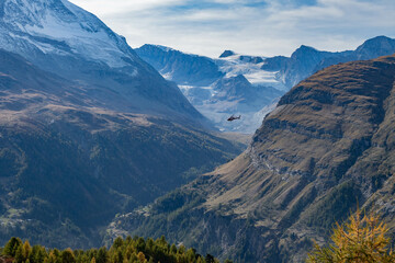 Obraz premium Helicopter flying in the remote alpine wilderness near Zermatt by the Matterhorn and Monte Rosa glacier
