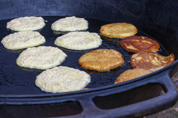Cooking potato pancakes in a pan in outdoor conditions