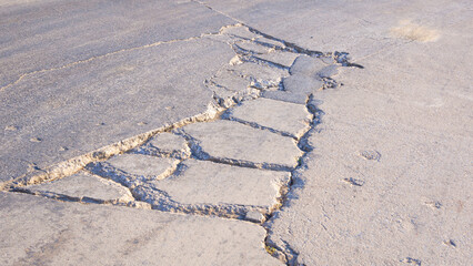 The old damaged concrete road with broken crack lines and collapsed texture on surface