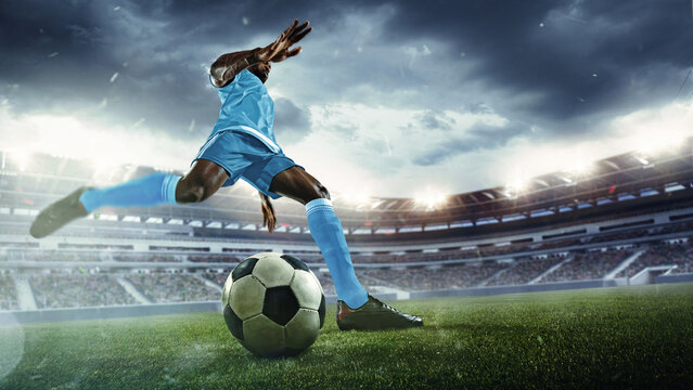 Dynamic image of man, soccer player in blue uniform preparing to kick ball on vibrant green field during intense match. 3D render of stadium. Concept of sport, tournament, competition, game event