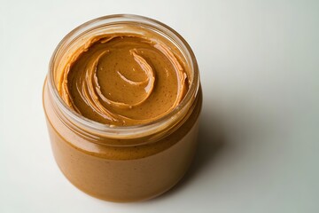 Open jar of creamy peanut butter on plain background