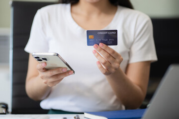 Businesswoman hand holding credit card and use laptop and smartphone in office.