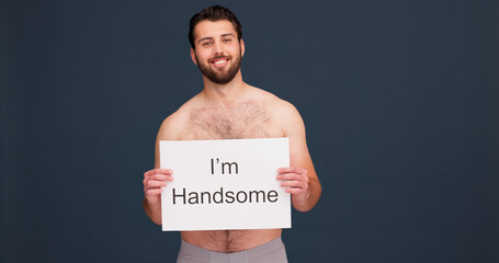 Studio, portrait and man with board for self love, confidence and happy pride with unique identity. Smile, empowerment and topless male person with poster sign for body positivity on dark background