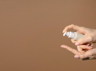 Banner Female hand holds a bottle with dispenser with cosmetic serum. Natural cosmetic product for skin purity and hydration. Unmarked bottle with product for face skin care.