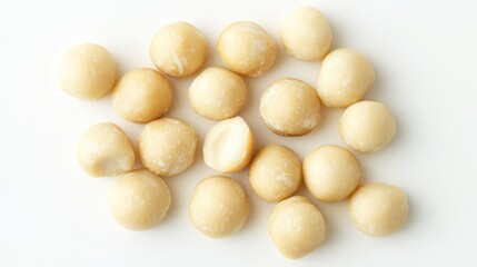 Raw macadamia nuts arranged on a clean white background showcasing their smooth texture and subtle color variations.
