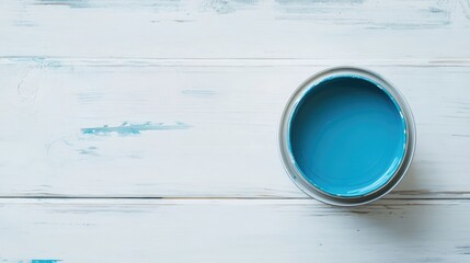 Blue paint can on white wooden surface top view with ample copy space for artistic or DIY design themes and projects.