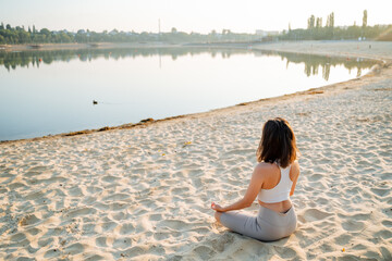 A serene woman finds deep peace and tranquility while meditating peacefully by the beautiful lakeside at sunrise, fully embracing the natural beauty surrounding her