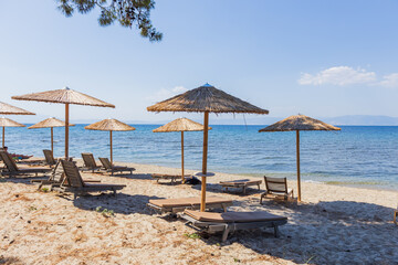 Straw Umbrellas And Sunbeds On Sandy Beach With Calm Blue Sea View