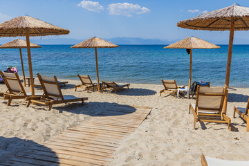 Straw Umbrellas And Sunbeds On Sandy Beach With Calm Blue Sea View