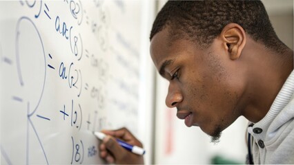 Focused young man solving math equations on whiteboard