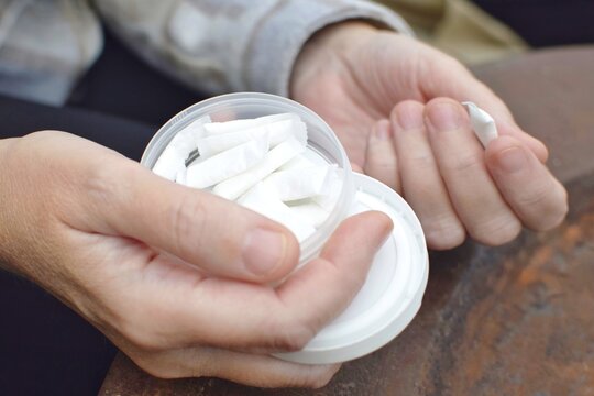 A box of snus pads replaces smokeless cigarettes. Swedish nicotine pouch. A woman holds one bag of snus in her hand.