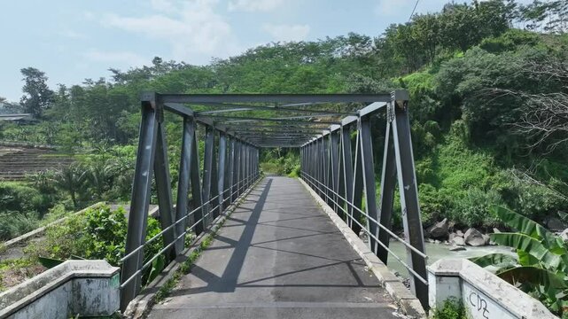 Video of B60 type steel truss bridge replacing the old collapsed bridge next to it over a clear river with stunning natural scenery