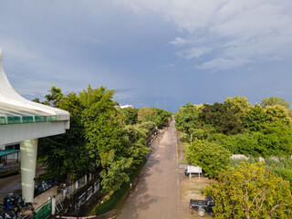 A road with trees on both sides and a white building in the background