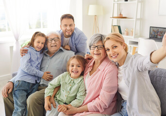 Portrait of happy cheerful big family of young parents, senior grandparents and two smiling children boy and girl looking at camera making selfie together sitting on sofa in living room at home.
