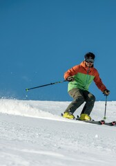 Adventurous winter skiing down snowy mountain slope in sunny weather. A young Brazilian man skiing down a snowy slope