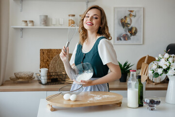 Beautiful girl housewife cooks in the kitchen