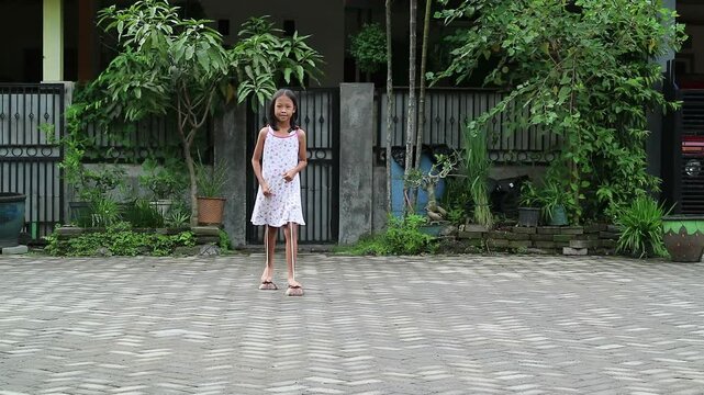 Cheerful Asian Indonesian little girl balances on stilts, joyful childhood moment that embodies the rich cultural heritage of Java. This traditional game usually called egrang