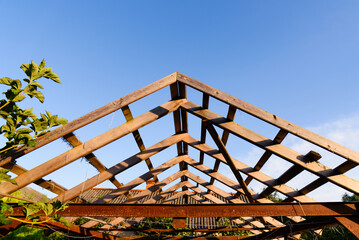 Wooden structure roof frame carport roof frame against blue sky, process of building a garage,...