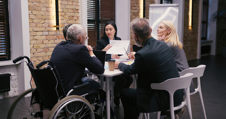 Diverse businesspeople discuss financial reports in office