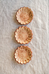 A selection of handmade stoneware ceramics in various glazes and decorations on a soft cloth background and setup
