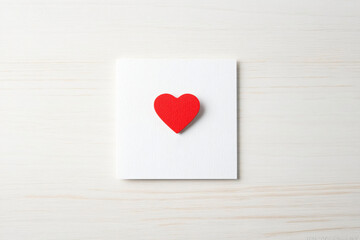 Fototapeta premium Red heart pinned white blank note, letter or valentine. Mockup poster design template for congratulation on Valentine's Day, March 8 or Mother's Day, declaration of love, date with place for text