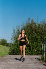 Beautiful girl in sportswear jogging outdoors in the park