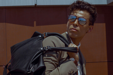 Handsome man holding travel bag on shoulder looking back