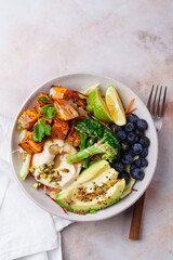 Balanced vegan bowl with baked sweet potato, avocado, berries, salad and hummus. Plant Based Diet Concept.