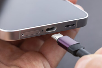 Close up of connecting usb c cable to the port of the modern phone. Charging modern phone