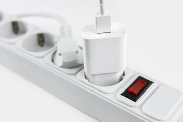 mobile phone chargers connected to electrical power strip. Various devices charging concept