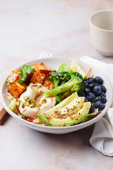 Balanced vegan bowl with baked sweet potato, avocado, berries, salad and hummus. Plant Based Diet Concept.