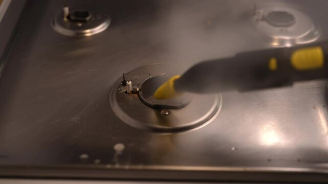 Close-up of meticulous sanitization of gas stove burner by steam cleaner, highlighting significance of maintaining kitchen hygiene and cleanliness. Concept of easy housekeeping domestic life.