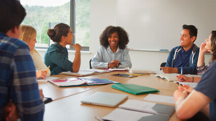 Female Tutor Teaching Class Of High School College Or University Students Sitting Around Table