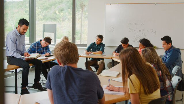 Male Tutor In Classroom Teaching High School College Or University Students In Maths Class