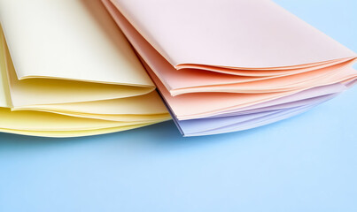Pastel-colored paper sheets arranged artfully on a light blue background.  Perfect for stationery, branding, or design projects.