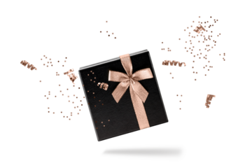 Black gift box with copper golden ribbon and confetti flying isolated on white background. Black friday or celebration concept. Ribbon and confetti in trendy color  Mocha Mousse.