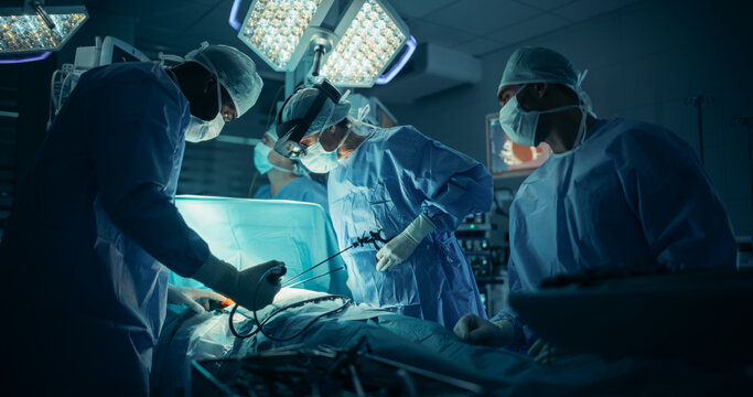Portrait of a Female Surgeon Using an AR Headset, Analyzing Vital Patient Data Only Visible in Extended Reality Glasses, as Her Team Helps with the Medical Operation in a Hospital