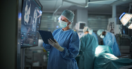 Lead Surgeon Reviews Critical Brain Scans Displayed on a Monitor as Well as Health Data on a Tablet Computer. Her Team Preparing as She Plans the Surgical Approach for the Operation