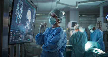 Professional Focused Caucasian Female Surgeon Reviewing Patient's Brain Scans on a Large Monitor,...