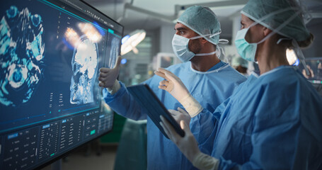 Portrait of a Young Female and Male Surgeons Reviewing Patient's Brain Scans on a Large Screen in a...