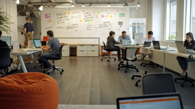 Laptop in focus on a wooden table with blurred creative people working on laptops in a coworking collaborative workspaces, space startup office