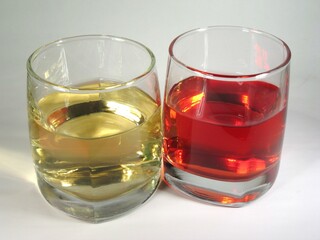 Red and white wine in transparent glasses over white background