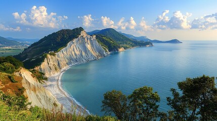 Panoramic view of scenic coastal cliffs, beach, and sea under a blue sky with clouds.