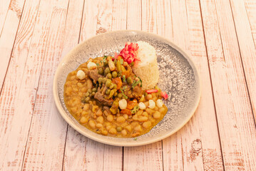 A plate of beans with rice, corn and spicy chili sauce