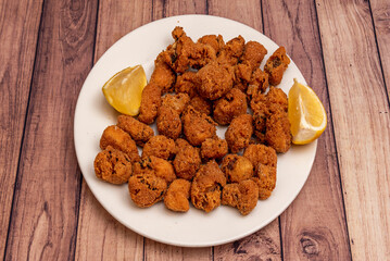 A plate of breaded fish with lemon slices