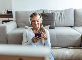 A young blond woman sitting on the floor and rests. She is listens to music and takes a break from moving apartment.