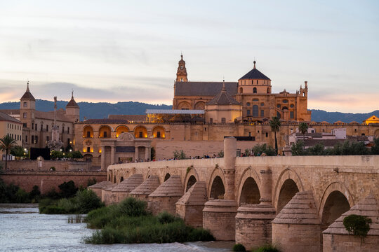 Córdoba, Spain - August 17, 2024: The Mosque-Cathedral with the Roman Bridge in the foreground at sunset