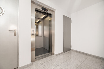 Landing of a house with white painted walls and stainless steel elevator