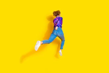 Full length photo of lovely young lady running fast back view dressed stylish colorful blue garment isolated on yellow color background