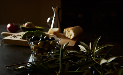 Rustic Mediterranean olives and baguette on a wooden kitchen counter